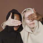 Calm women covering eyes of each other