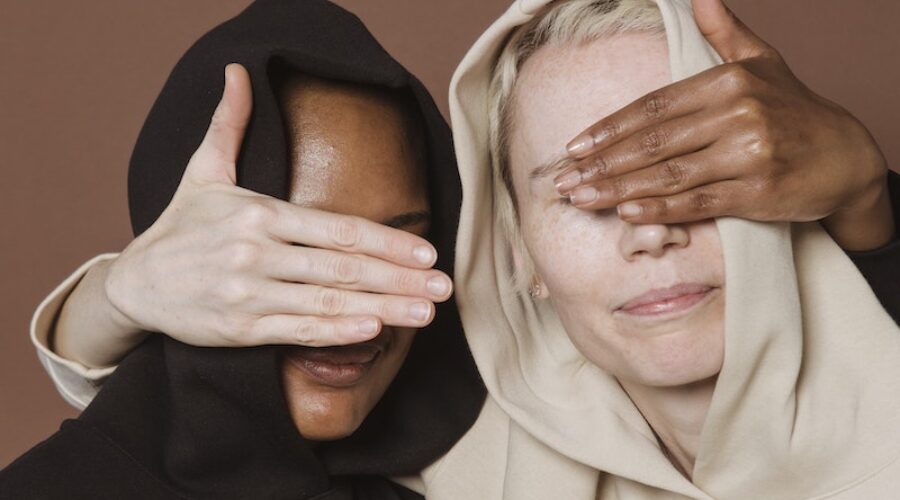 Calm women covering eyes of each other