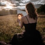 woman in black spaghetti strap dress sitting on brown log during daytime