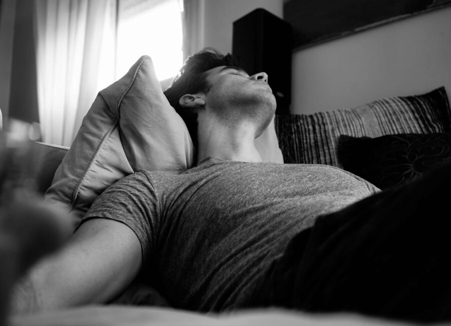 grayscale photo of man laying on bed